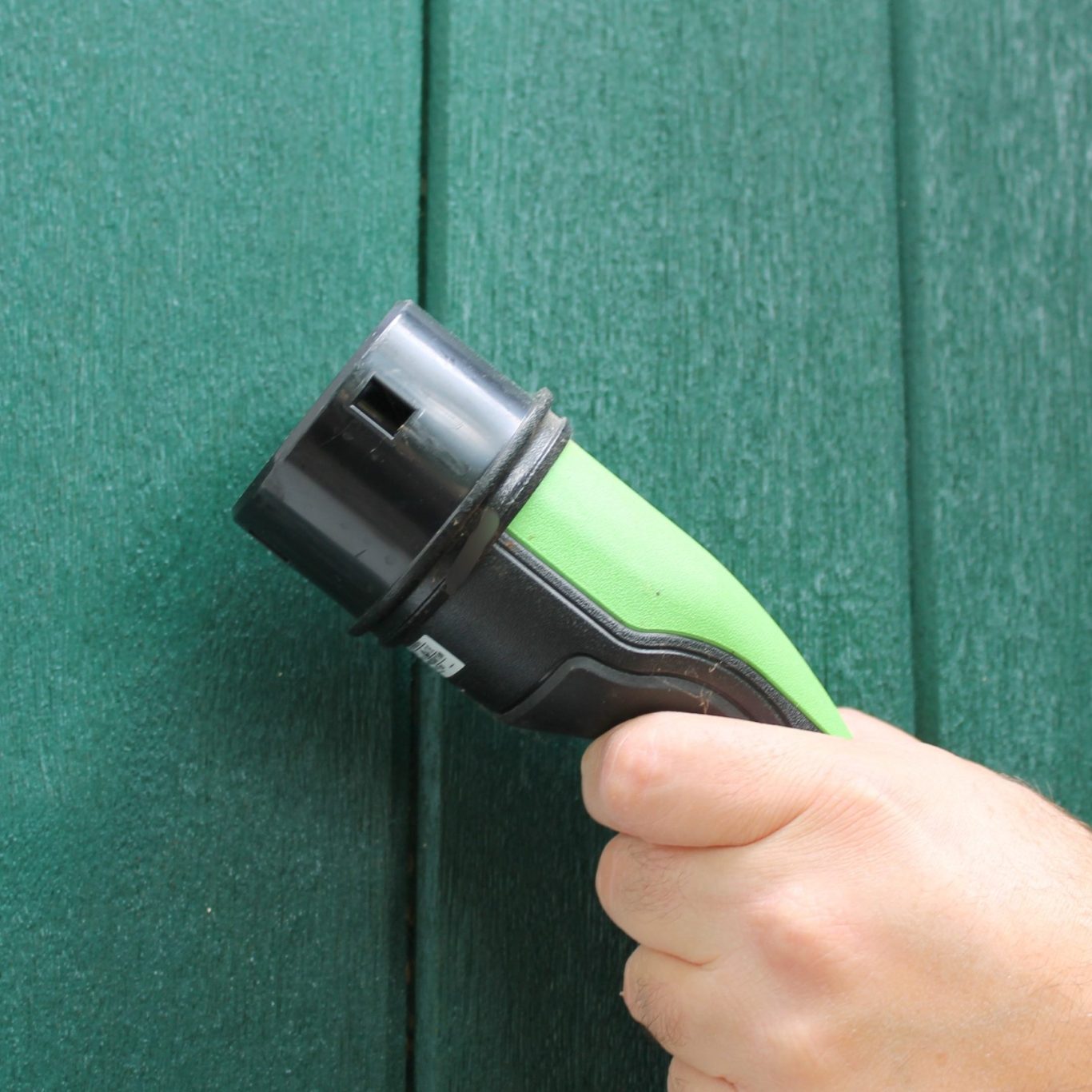 Das Bild zeigt eine Hand mit einem Stecker einer Wallbox. 