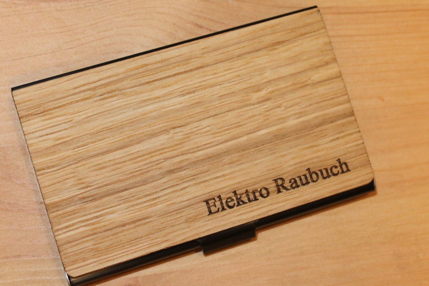 Das Bild zeigt ein Etui aus Holz mit der Aufschrift "Elektro Raubuch" auf einem Tisch.